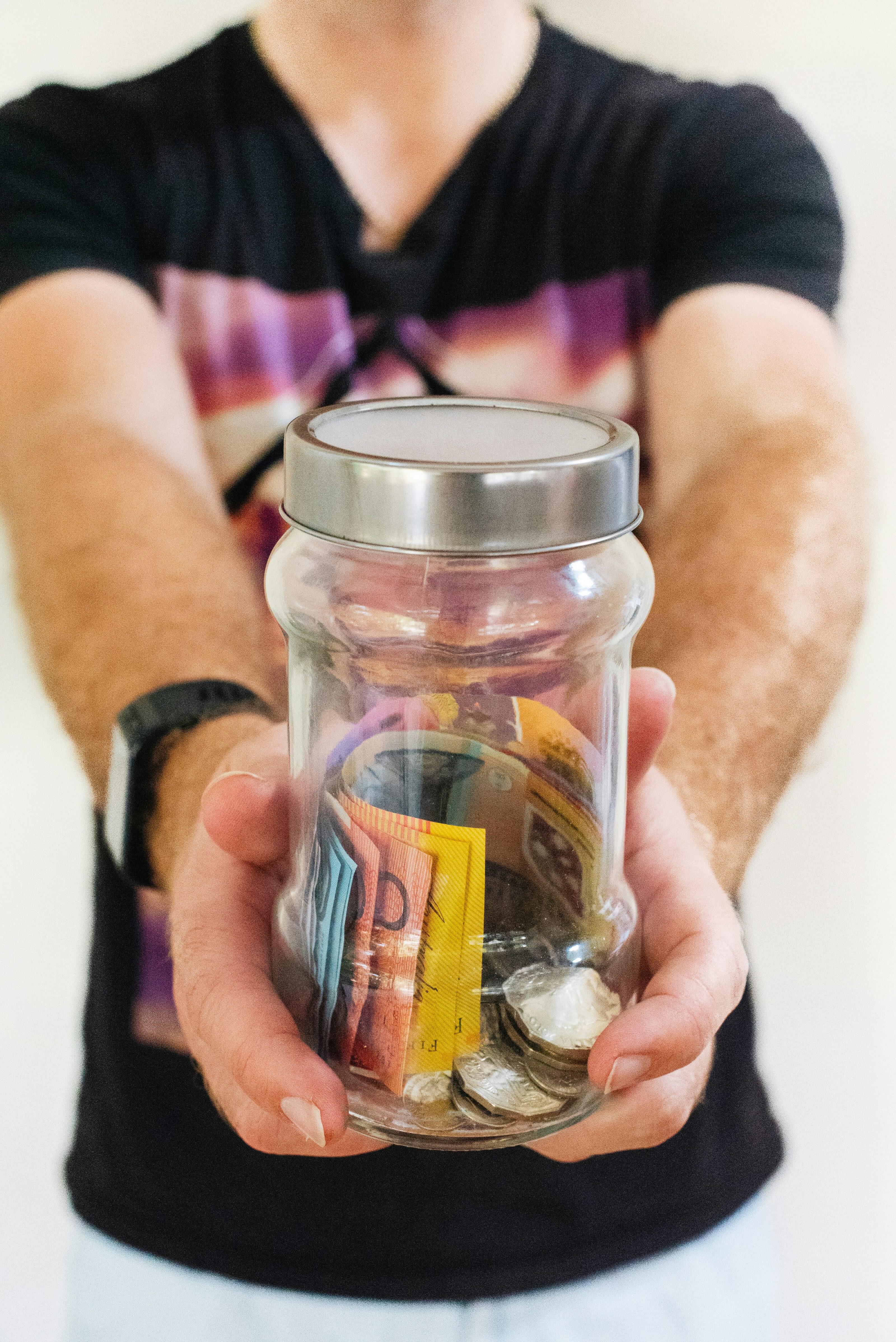 Mann mit klarem Glasgefäß voller Geld